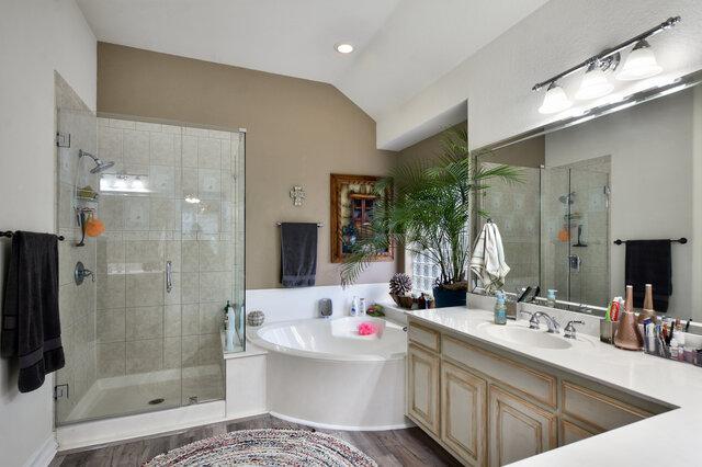 1906 W Moeta Dr, Austin, TX 78734 - bathroom featuring a bath, a shower stall, vanity, lofted ceiling, and wood finished floors