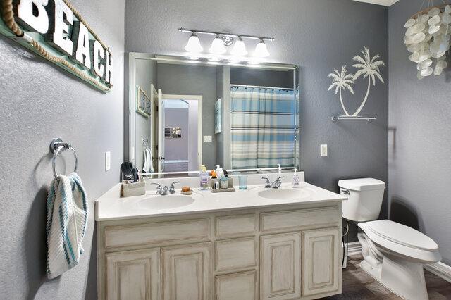 1906 W Moeta Dr, Austin, TX 78734 - bathroom featuring double vanity, a textured wall, and curtained shower
