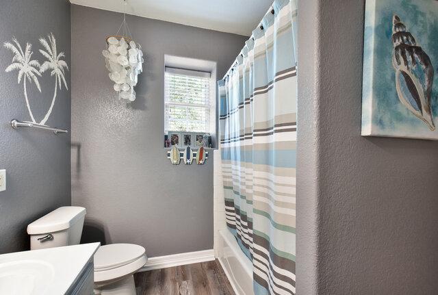 1906 W Moeta Dr, Austin, TX 78734 - full bathroom with vanity, wood finished floors, a textured wall, and shower / bath combo