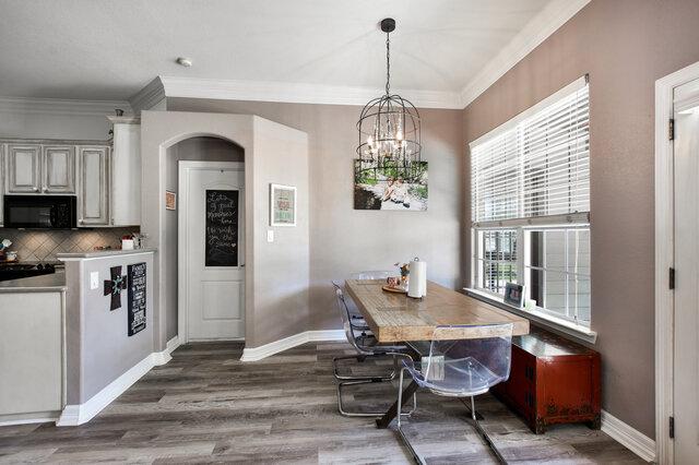 1906 W Moeta Dr, Austin, TX 78734 - dining space featuring healthy amount of natural light, crown molding, a chandelier, wood finished floors, and arched walkways