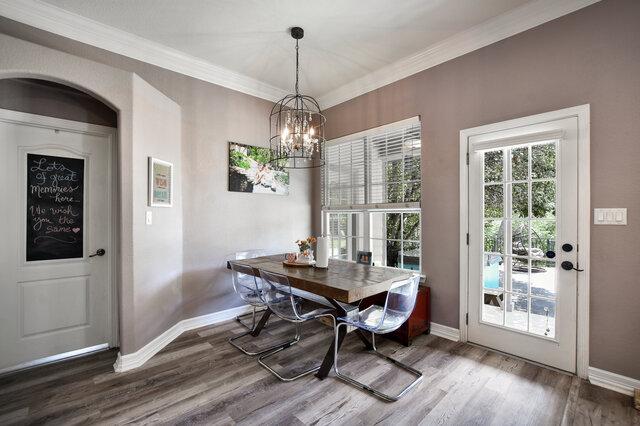 1906 W Moeta Dr, Austin, TX 78734 - dining room featuring wood finished floors, crown molding, and a chandelier