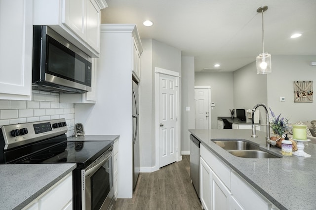 125 Hawea Ln, Bastrop, TX 78602 - kitchen with appliances with stainless steel finishes, dark wood finished floors, white cabinets, decorative backsplash, and decorative light fixtures