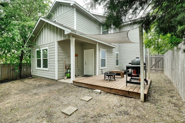 125 Hawea Ln, Bastrop, TX 78602 - back of property with board and batten siding, a fire pit, a wooden deck, and a fenced backyard