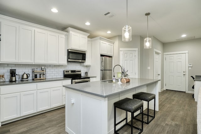 125 Hawea Ln, Bastrop, TX 78602 - kitchen with appliances with stainless steel finishes, tasteful backsplash, white cabinets, dark wood-type flooring, and a breakfast bar area