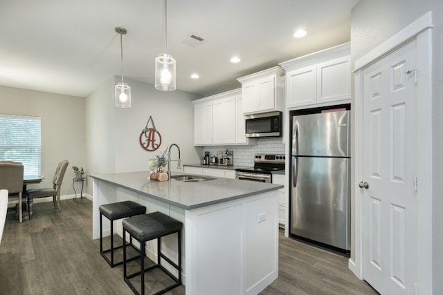 125 Hawea Ln, Bastrop, TX 78602 - kitchen with stainless steel appliances, dark wood-type flooring, an island with sink, decorative backsplash, and white cabinetry