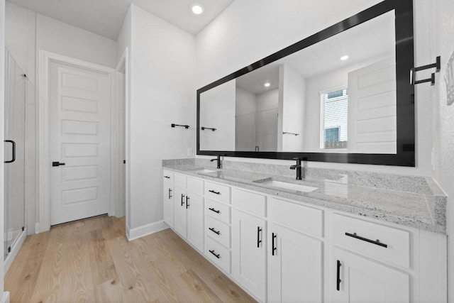 17224 Autumn Falls Dr, Manor, TX 78653 - bathroom with double vanity, a shower stall, wood finished floors, and recessed lighting