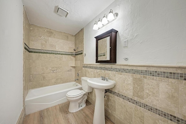 2705 Sabinal Trl, Cedar Park, TX 78613 - full bathroom with tile walls, wood finished floors, shower / washtub combination, and wainscoting