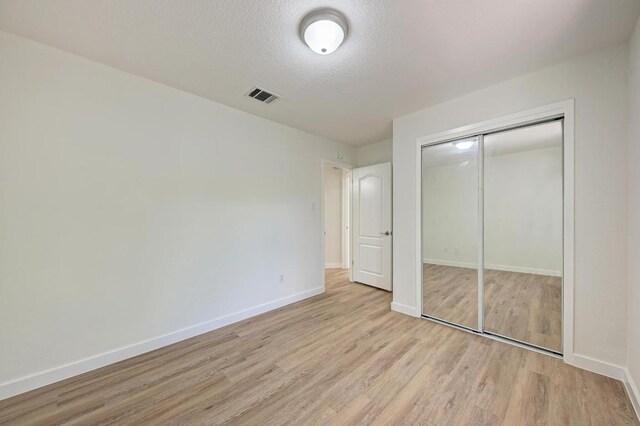 2705 Sabinal Trl, Cedar Park, TX 78613 - unfurnished bedroom with light wood-type flooring, a textured ceiling, and a closet