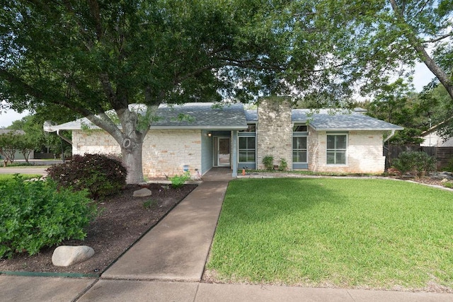 3801 Oak Creek Dr, Austin, TX 78727 - view of front of property featuring a front yard, stone siding, a chimney, and roof with shingles