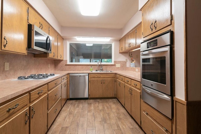 3801 Oak Creek Dr, Austin, TX 78727 - kitchen with appliances with stainless steel finishes, a warming drawer, backsplash, light wood-type flooring, and light countertops