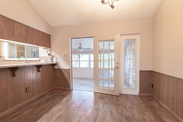 3801 Oak Creek Dr, Austin, TX 78727 - unfurnished dining area with wood finished floors, a wainscoted wall, lofted ceiling, wooden walls, and a textured ceiling
