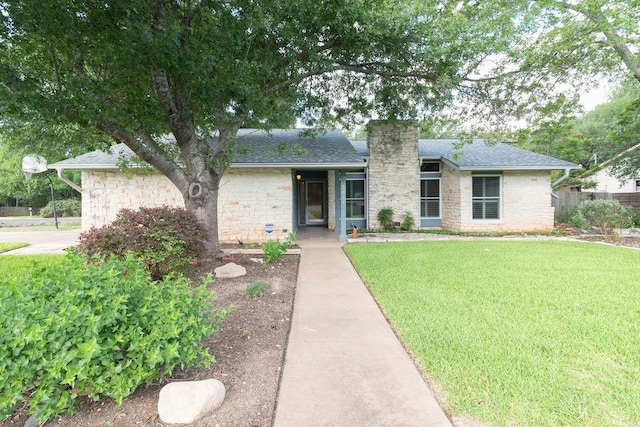 3801 Oak Creek Dr, Austin, TX 78727 - view of front of house with stone siding, a chimney, a front yard, and roof with shingles