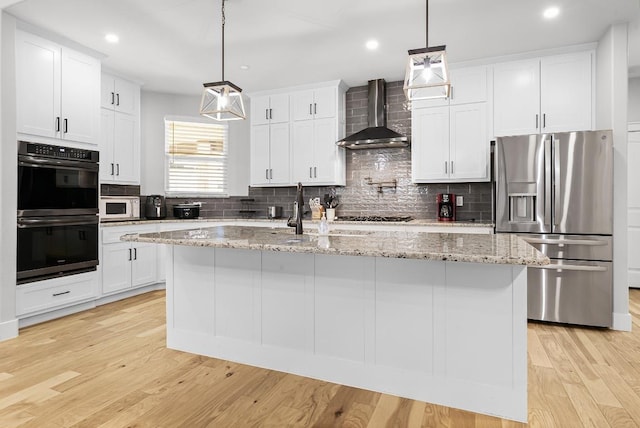 110 Les Ln, Smithville, TX 78957 - kitchen featuring appliances with stainless steel finishes, wall chimney range hood, tasteful backsplash, an island with sink, and recessed lighting