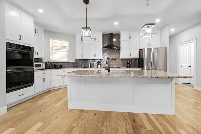 110 Les Ln, Smithville, TX 78957 - kitchen with stainless steel appliances, wall chimney exhaust hood, backsplash, a kitchen island with sink, and white cabinetry