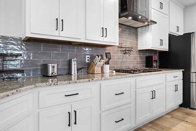 110 Les Ln, Smithville, TX 78957 - kitchen with wall chimney exhaust hood, gas cooktop, white cabinets, and decorative backsplash
