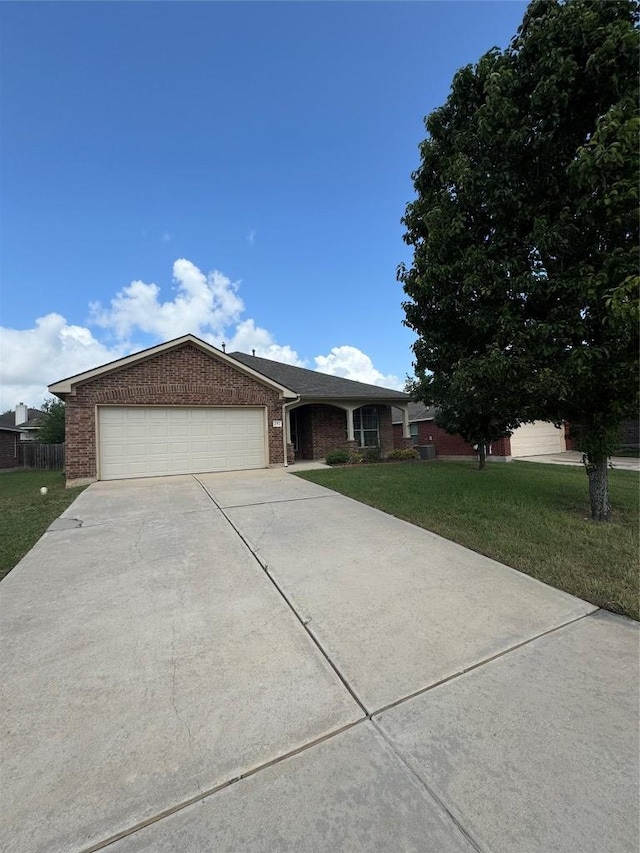 257 Firwood N, Kyle, TX 78640 - ranch-style house featuring concrete driveway, an attached garage, brick siding, and a front lawn