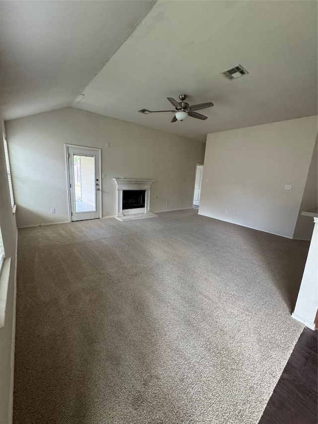 257 Firwood N, Kyle, TX 78640 - unfurnished living room with a ceiling fan, a fireplace with raised hearth, vaulted ceiling, and carpet