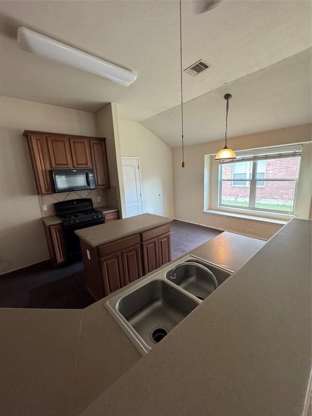 257 Firwood N, Kyle, TX 78640 - kitchen with black appliances, a kitchen island, brown cabinets, lofted ceiling, and decorative light fixtures