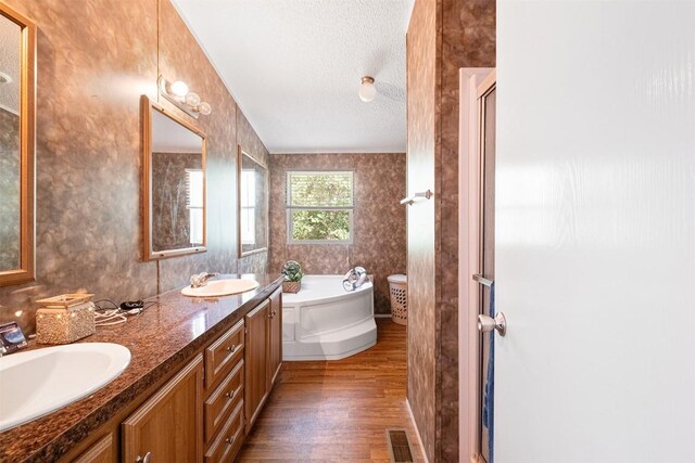 1231 Peach Creek Rd, Waelder, TX 78959 - full bathroom featuring wood finished floors, a bath, a textured ceiling, double vanity, and a shower with shower door