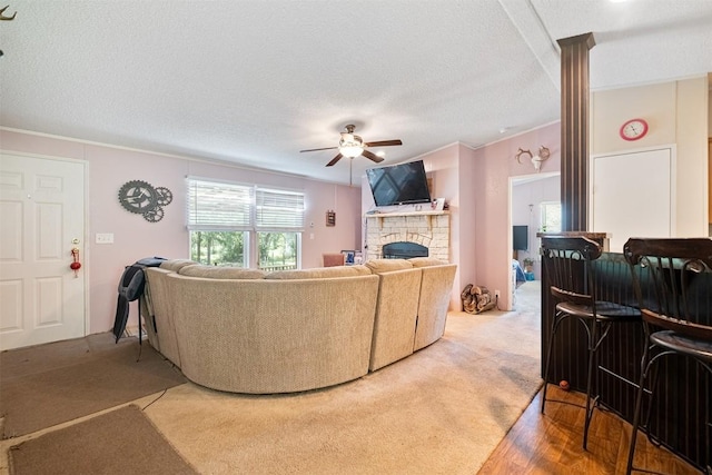 1231 Peach Creek Rd, Waelder, TX 78959 - carpeted living room featuring a ceiling fan, a stone fireplace, crown molding, a textured ceiling, and a dry bar