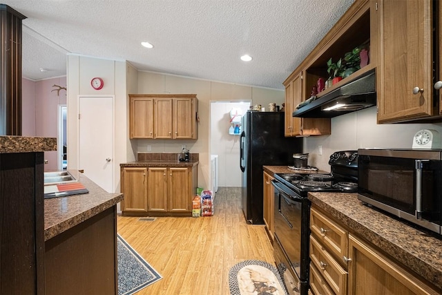1231 Peach Creek Rd, Waelder, TX 78959 - kitchen featuring black appliances, exhaust hood, light wood-style floors, lofted ceiling, and dark countertops
