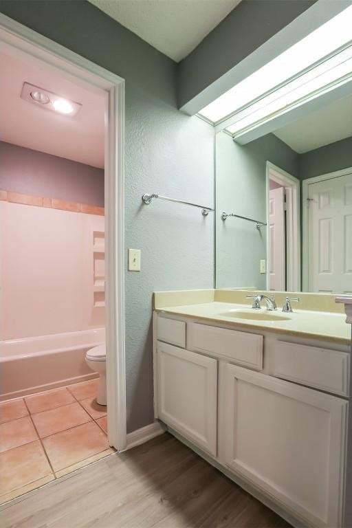 3111 Tom Green St Unit 105, Austin, TX 78705 - full bathroom with vanity, wood finished floors, bathing tub / shower combination, and a textured wall
