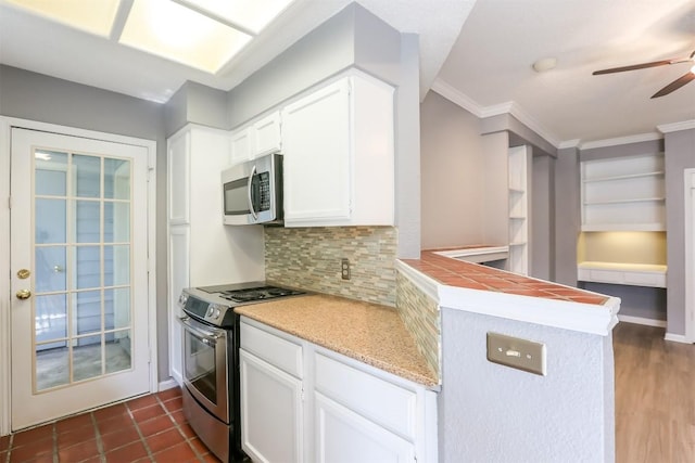 3111 Tom Green St Unit 105, Austin, TX 78705 - kitchen featuring stainless steel appliances, a ceiling fan, backsplash, white cabinets, and ornamental molding