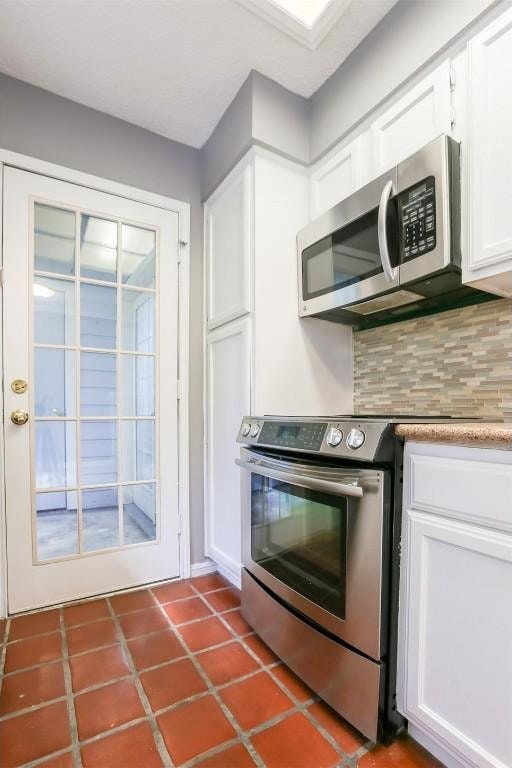 3111 Tom Green St Unit 105, Austin, TX 78705 - kitchen with appliances with stainless steel finishes, tasteful backsplash, white cabinetry, tile patterned flooring, and light countertops