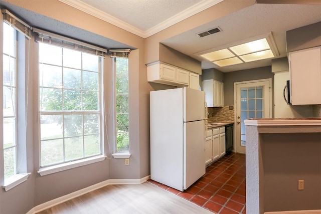 3111 Tom Green St Unit 105, Austin, TX 78705 - kitchen with freestanding refrigerator, black dishwasher, crown molding, tasteful backsplash, and white cabinets