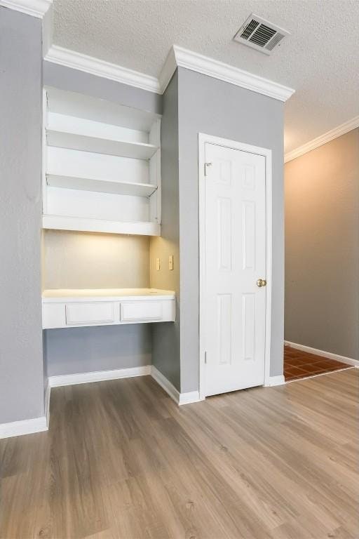 3111 Tom Green St Unit 105, Austin, TX 78705 - unfurnished office featuring crown molding, wood finished floors, built in desk, and a textured ceiling