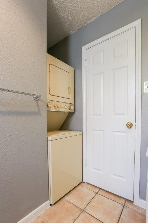 3111 Tom Green St Unit 105, Austin, TX 78705 - laundry room featuring stacked washer / drying machine, light tile patterned floors, a textured wall, and a textured ceiling