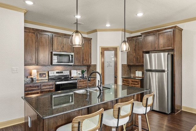 7606 Hickman St, Temple, TX 76502 - kitchen featuring appliances with stainless steel finishes, ornamental molding, dark wood finished floors, an island with sink, and a kitchen bar