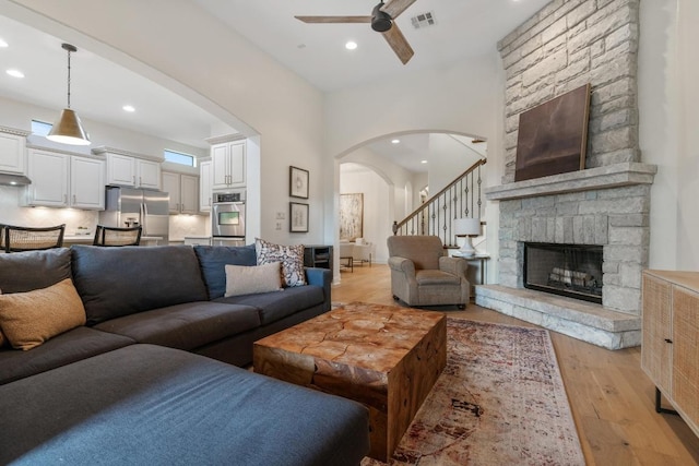 114 Reflection Bay Ct, Austin, TX 78738 - living room with arched walkways, ceiling fan, recessed lighting, light wood-type flooring, and a stone fireplace