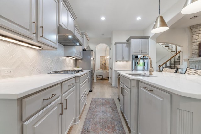 114 Reflection Bay Ct, Austin, TX 78738 - kitchen featuring arched walkways, exhaust hood, appliances with stainless steel finishes, decorative backsplash, and light wood-style floors