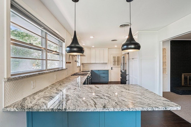 3806 Las Cienega Blvd, Temple, TX 76502 - kitchen with high end refrigerator, light stone counters, white cabinets, hanging light fixtures, and a peninsula