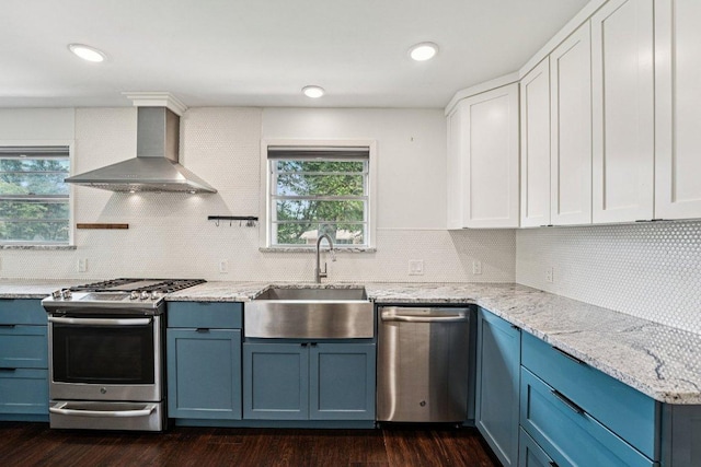 3806 Las Cienega Blvd, Temple, TX 76502 - kitchen with appliances with stainless steel finishes, wall chimney exhaust hood, blue cabinets, dark wood finished floors, and recessed lighting