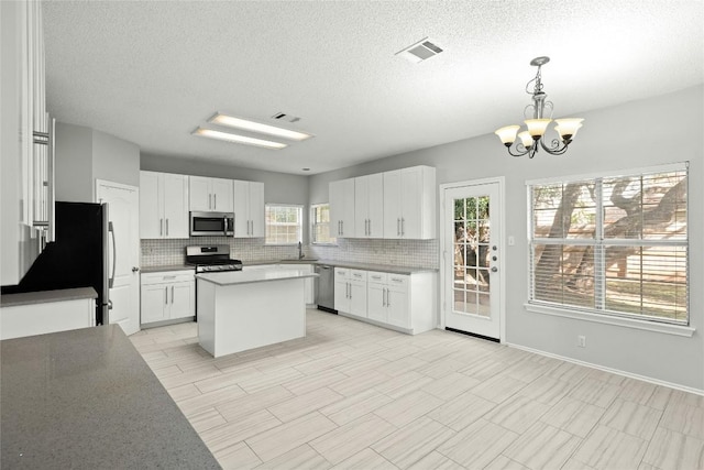 1217 Dove Cir, Cedar Park, TX 78613 - kitchen with stainless steel appliances, tasteful backsplash, a chandelier, a textured ceiling, and white cabinetry