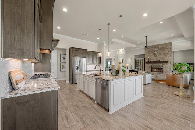 105 Clear Springs Ct, Marble Falls, TX 78654 - kitchen featuring stainless steel appliances, crown molding, tasteful backsplash, a stone fireplace, and open floor plan