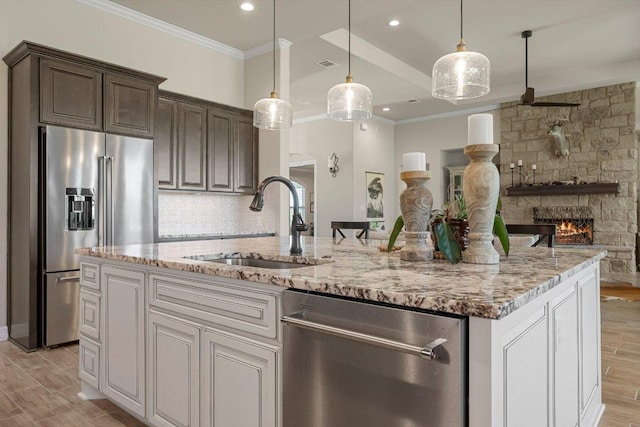 105 Clear Springs Ct, Marble Falls, TX 78654 - kitchen featuring appliances with stainless steel finishes, crown molding, light stone counters, a stone fireplace, and dark brown cabinets