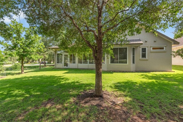 140 Whispering Wind Dr, Georgetown, TX 78633 - rear view of house featuring a yard, a sunroom, and stucco siding
