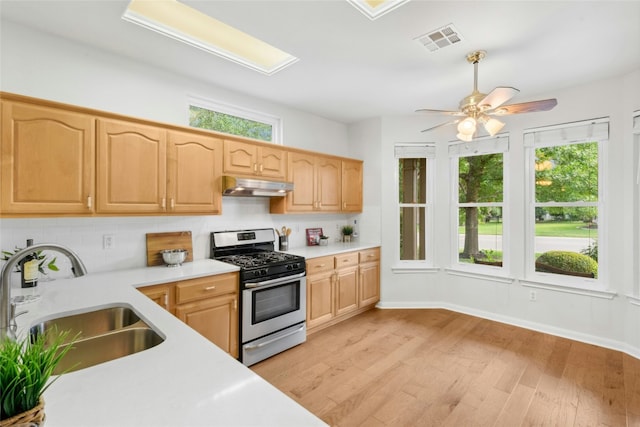 140 Whispering Wind Dr, Georgetown, TX 78633 - kitchen with gas range, under cabinet range hood, light countertops, and plenty of natural light