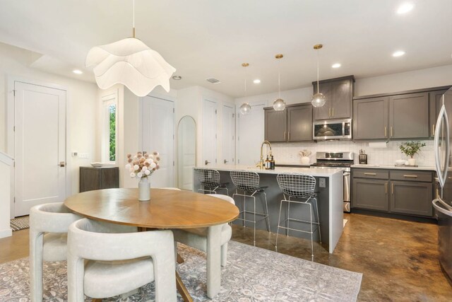 6204 Hickman Ave Unit A, Austin, TX 78723 - kitchen with stainless steel appliances, finished concrete flooring, backsplash, recessed lighting, and a kitchen island with sink