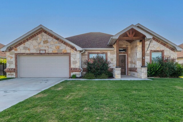 249 Pecan Meadow Ln, Belton, TX 76513 - view of front of home with stone siding, an attached garage, a front lawn, concrete driveway, and a shingled roof