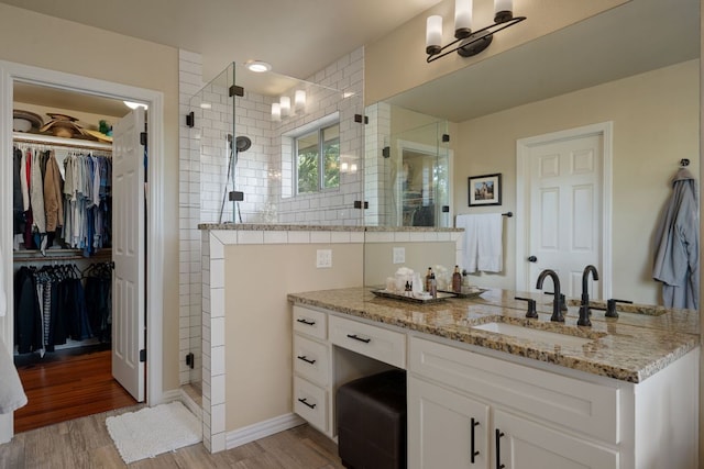 7709 Waldon Dr, Austin, TX 78750 - bathroom with a stall shower, vanity, a walk in closet, and wood finished floors