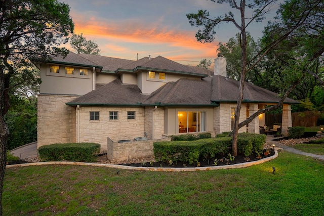 7709 Waldon Dr, Austin, TX 78750 - view of front of home featuring stone siding, a chimney, a lawn, stucco siding, and a shingled roof
