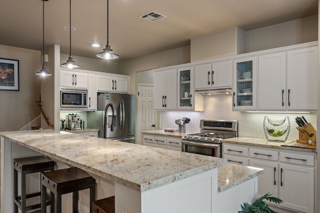7709 Waldon Dr, Austin, TX 78750 - kitchen with stainless steel appliances, white cabinets, decorative backsplash, ventilation hood, and a kitchen breakfast bar