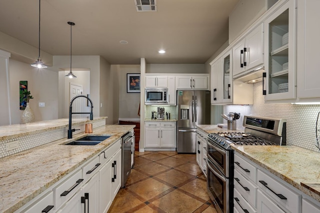 7709 Waldon Dr, Austin, TX 78750 - kitchen with appliances with stainless steel finishes, white cabinets, tasteful backsplash, hanging light fixtures, and glass insert cabinets