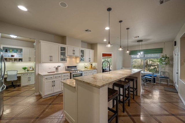 7709 Waldon Dr, Austin, TX 78750 - kitchen with gas stove, tasteful backsplash, recessed lighting, and white cabinetry