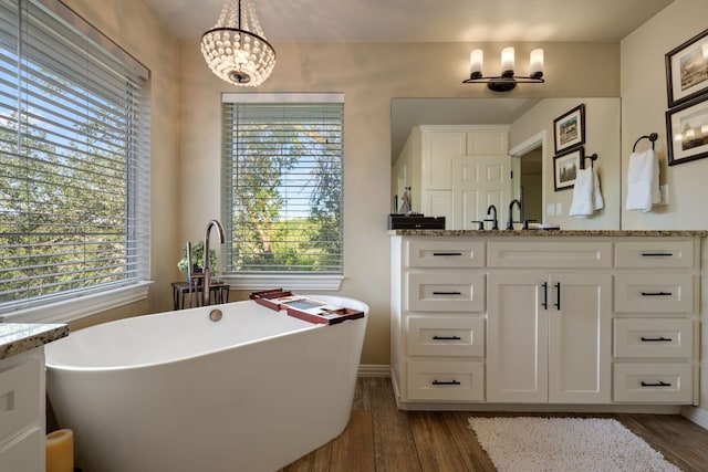 7709 Waldon Dr, Austin, TX 78750 - bathroom with vanity, a chandelier, wood finished floors, and a freestanding tub