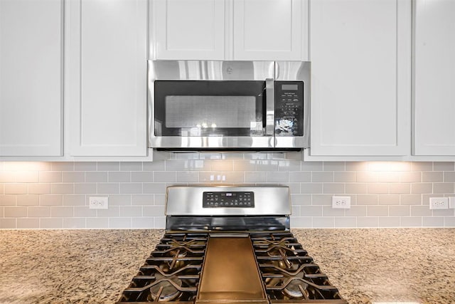 1017 Sundrops St, Leander, TX 78641 - kitchen view of stainless steel appliances, white cabinets, backsplash, and light stone countertops